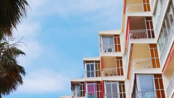 Güneşli İspanya 'da güneşli bir günde rüzgarla mavi gökyüzüne karşı hafifçe hareket eden tenteli eski apartman balkonları ve pencereler alçak açılı. — Stok video