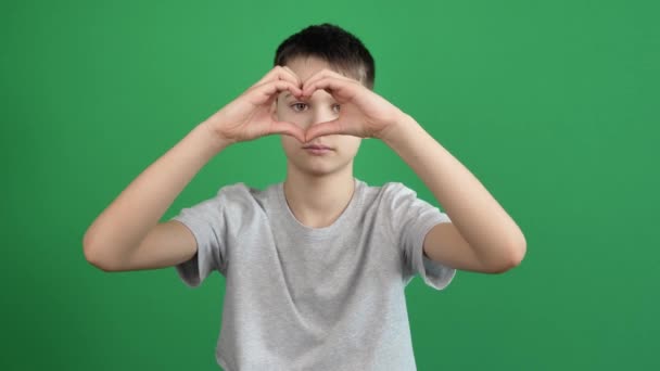 Mãos de menino fazendo gesto de forma de coração no fundo de cromo tela verde. A pessoa forma o coração usando os dedos — Vídeo de Stock