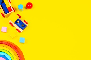 Bebek oyuncakları geçmişi. Tahta oyuncak tren, ahşap gökkuşağı ve sarı arka planda renkli bloklar. Üst manzara, düz uzanma