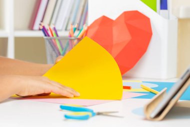 Çocuk elleri tablet bilgisayarda video dersi izleyen origami ya da renkli kağıt kart beyazı yaratır. Eğitim, öğrenim, kağıt işçiliği, evde eğlence