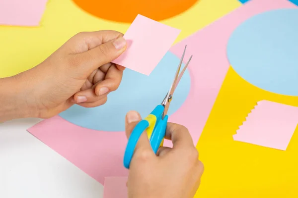 Manos cortando papel de colores con tijeras. Educación, aprendizaje, artesanía del papel, entretenimiento en el hogar — Foto de Stock