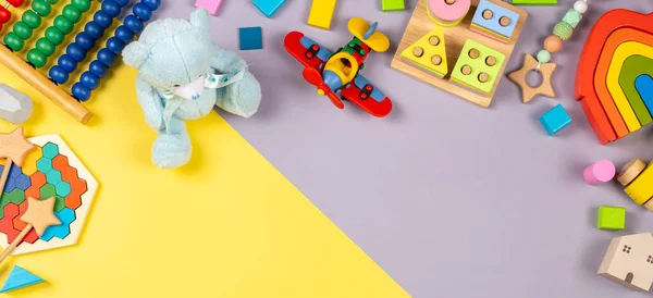 Dětské hračky rámeček. Barevné vzdělávací dřevěné plastové a nadýchané hračky pro děti na žlutém a šedém pozadí. Pohled shora, byt ležel — Stock fotografie