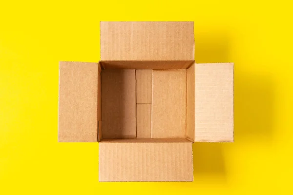 Sarı arka planda boş bir karton kutu. Üst görünüm, alanı kopyala — Stok fotoğraf