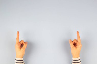 Açık gri arkaplan üzerinde işaret parmağıyla işaret eden kadın elleri