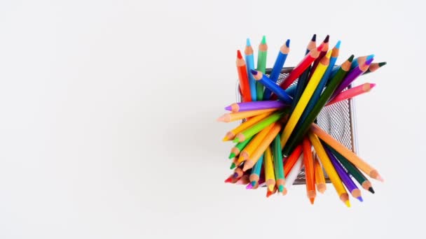 Birçok renkli kalemler beyaz masadaki metal kalem tutacağında duruyor ve birbiri ardına ortadan kayboluyor. Üst Manzara. Hareket animasyonunu durdur. 4K — Stok video