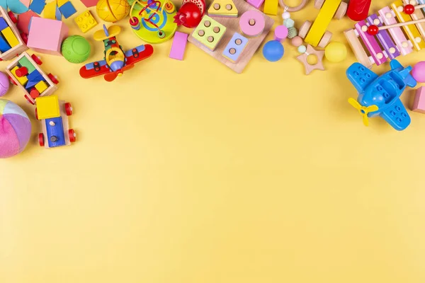 Oyuncak bebek çerçevesi. Renkli eğitici ahşap plastik ve pastel sarısı arka plandaki çocuklar için tüylü oyuncaklar. Üst manzara, düz uzanma — Stok fotoğraf