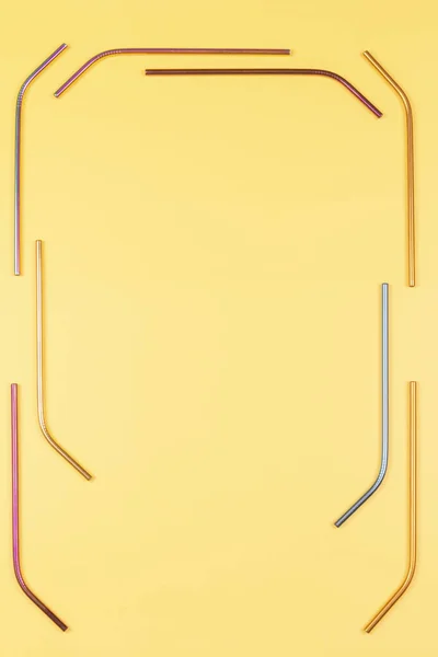 Різнокольорові багаторазові соломинки з нержавіючої сталі на пастельному жовтому тлі. Вид зверху, простір для копіювання — стокове фото