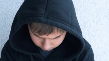 Siyah kapüşonlu ceketli genç başını kaldırıp doğrudan kameraya bakıyor. Kapıları kapatın. 4k video