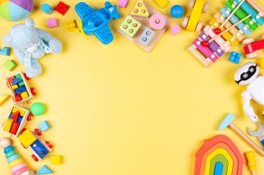 Renkli eğitici ahşap plastik ve pastel sarısı arka plandaki çocuklar için tüylü oyuncaklar. Üst manzara, düz uzanma