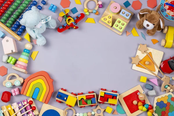 Babyspielzeug umrahmt. Bunte pädagogische Holzkunststoffe und flauschige Kinderspielzeuge auf grauem Hintergrund. Ansicht von oben — Stockfoto