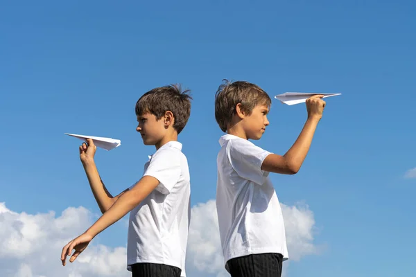 Två pojkar leker med papper flygplan mot blå sommar himmel bakgrund — Stockfoto