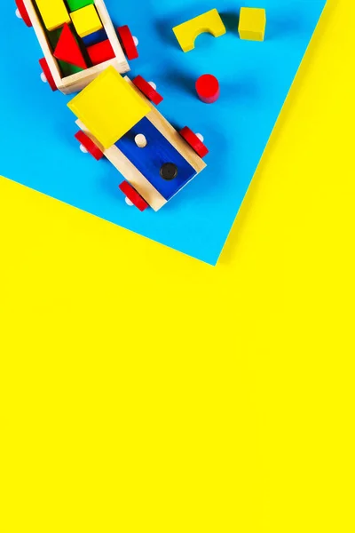 Babyspielzeug Hintergrund. Holzspielzeugeisenbahn mit bunten Blöcken auf hellblauem und gelbem Hintergrund. Ansicht von oben — Stockfoto