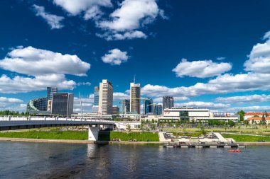 Vilnius, Litvanya - 12 Mayıs 2021: İnsanlar güneşli hafta sonunun tadını çıkarıyor. Neris Nehri, Beyaz Köprü ve Gökdelenleri olan Vilnius şehri