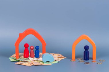 Boşanma, ebeveynler arasındaki anlaşmazlık, çocukların velayeti, mal paylaşımı. Ahşap evler, aile ve çocukların minyatür figürleri, gri arka planda nakit para.