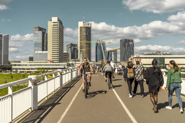 Vilnius, Lituania - 30 de mayo de 2021: Personas caminando, montando bicicletas y scooters en el puente Blanco. Paisaje urbano de Vilna con el río Neris — Foto de Stock