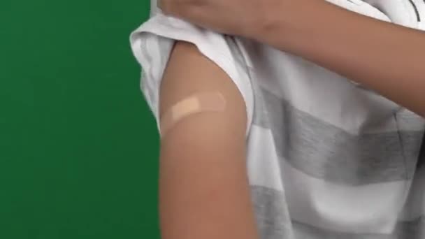 Tinédzser fiú mutatja a karját vakolat után oltás zöld képernyős háttér. Vakcina és egészségügyi ellátás a kovid-19 világjárvány idején — Stock videók
