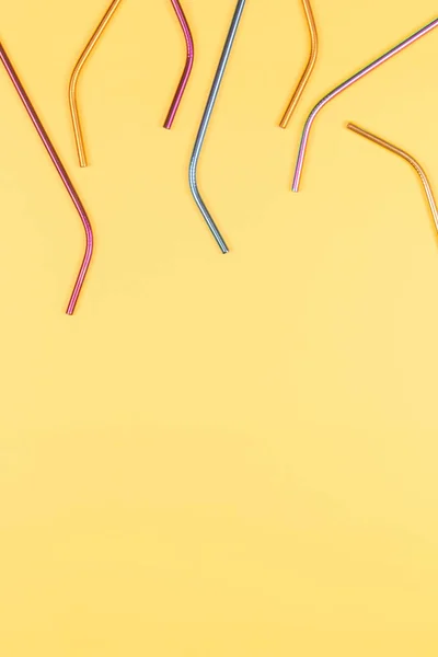 Többszínű újrahasznosítható rozsdamentes acél szívószálak pasztell sárga háttérrel. Felülnézet, másolás — Stock Fotó