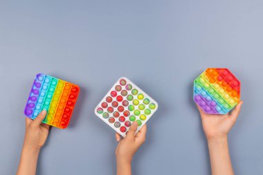 Birçok el mavi arka planda hareketli oyuncakları tutuyor. Kıpır kıpır hareket oyunu stresi ve endişeyi azaltmaya yardımcı olur.