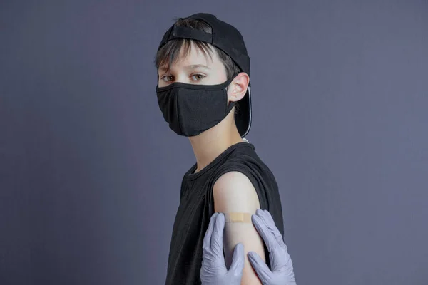 Enfermeira em luvas de proteção de borracha colocando bandagem de gesso no braço do menino adolescente após a vacinação. Vacina injectável covid, cuidados de saúde para crianças — Fotografia de Stock