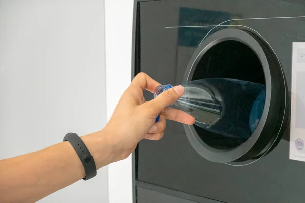 Otomatı ters çevir. Kadın eli boş plastik şişeyi makineye koydu. Metal içki kutuları, plastik ve cam şişeler için geri ödeme ve geri dönüşüm otomatı