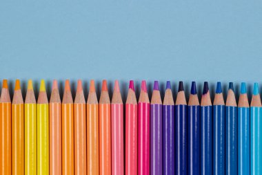 Açık mavi arkaplanda renkli kalem çerçevesi. Üst Manzara. Öğrenme, sanat, çeşitlilik, yaratıcı eğlence konsepti