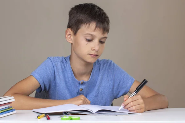 Pojkhanden håller pennan i vänster hand och skriver i en anteckningsbok, gör läxor. Vänsterhandsdagen — Stockfoto