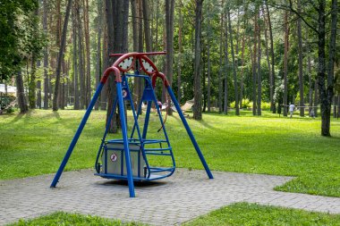 Güneşli yaz gününde şehir parkında tekerlekli sandalyeli çocuklar için salıncak