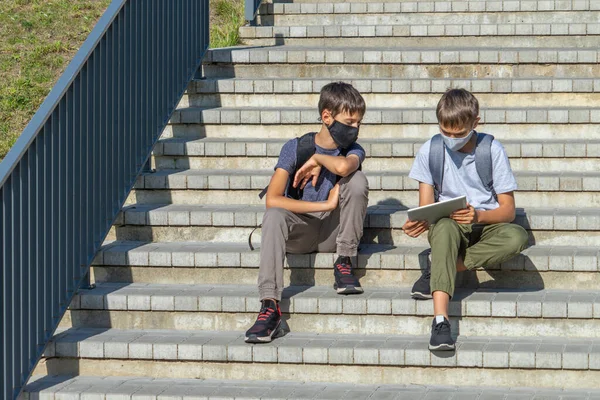 Adolescentes sentados afuera en las escaleras, usan tableta digital juntos y hablan — Foto de Stock