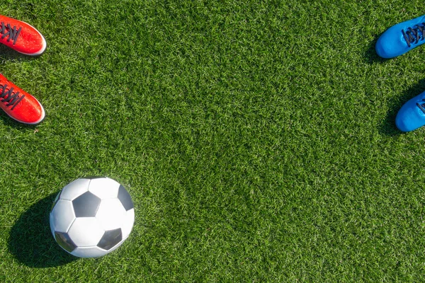 Soccer football background. Soccer ball and two pair of football sports shoes on artificial turf soccer field