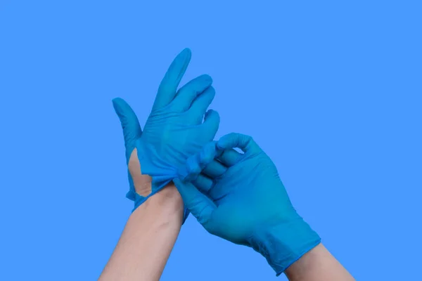 Mulher mãos decolando rasgado luvas de borracha azul — Fotografia de Stock