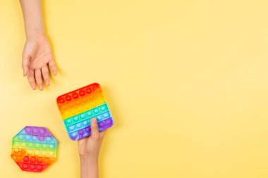 Çocukların elleri sarı arka planda yeni moda pop müziği oyuncağını alır ve verir. Üst görünüm