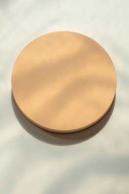 Beyaz zemin üzerinde doğal ışık ve gölgelerle dolu, boş, pastel bej bir platform podyumu. Kozmetik ürün sunumu için arka planı düzenle. Üst görünüm