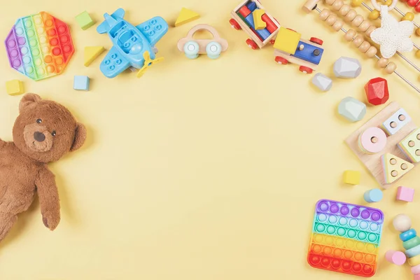 Baby Kinder Spielzeug Hintergrund mit Teddybär, Holz-und Musikspielzeug, Abacus, Pop it Fidget Spielzeug auf gelbem Hintergrund — Stockfoto