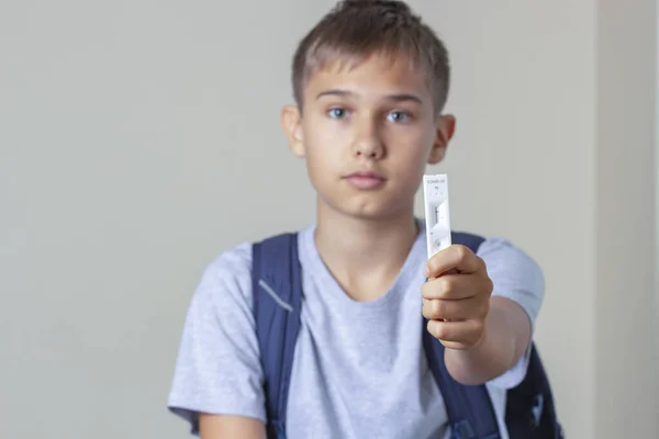 Menino adolescente com mochila mostra rápido Coronavirus Covid-19 dispositivo de teste negativo com resultado negativo — Fotografia de Stock
