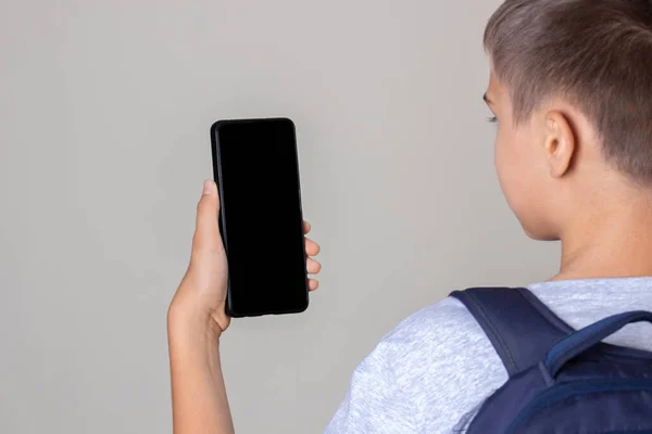 Adolescente segurando celular, olhando para a tela, lendo, assistindo vídeo, ouvindo mensagem de voz. Vista traseira — Fotografia de Stock