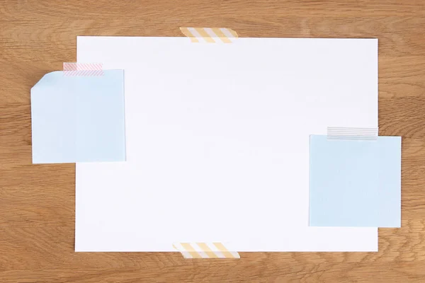 Página de papel branco em branco e notas coladas com fita adesiva no fundo de madeira — Fotografia de Stock