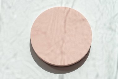 Beyaz zemin üzerinde doğal ışık ve gölgelerle dolu, boş, pastel bej bir platform podyumu. Kozmetik ürün sunumu için arka planı düzenle. Üst görünüm