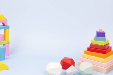 Educational kid toys background. Montessori wooden toys standing on light blue background. Front view.