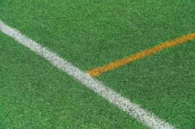 Yeşil sentetik çimen, sarı ve beyaz çizgileri olan yapay çim spor sahası.