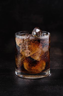 Serinletici içecek, buzlu soğuk soda ve siyah arka planda bir bardak.
