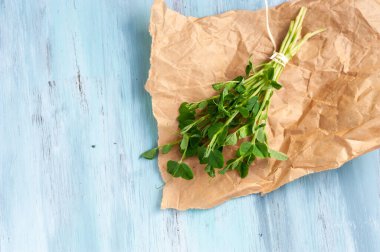 yeşil taze bezelye filizleri kağıt üzerinde ve mavi ahşap arka planda