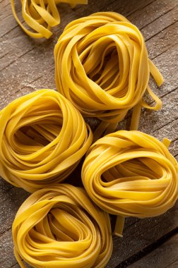 Ev yapımı makarna eski ahşap bir arka planda yuvalara yuvarlandı. Yukarıdan görüntüle