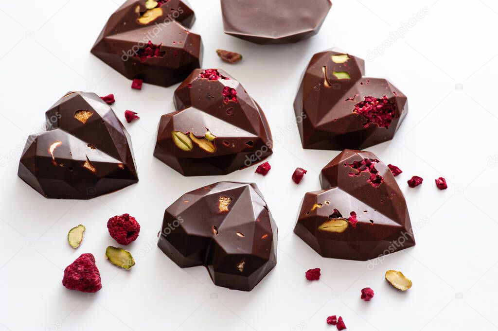 chocolates, in the form of hearts with milk and dark chocolate with pistachios and raspberries, handmade, top view