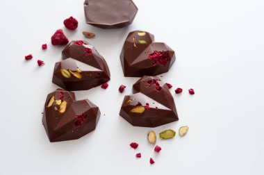 Kalpler şeklinde çikolatalar, sütlü çikolata, şam fıstığı ve ahududu, el yapımı, üst görünüm.