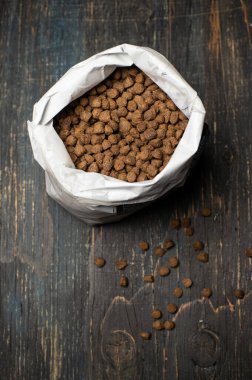 Tahta bir arka planda ambalaj poşetinde granüllerdeki kuru ve besleyici yiyecekler.