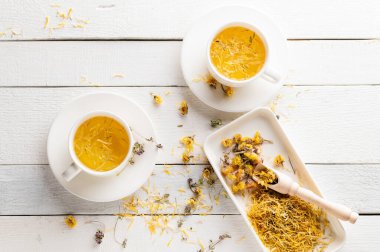 İki fincan aromatik çiçek çayı, sakinleştirici, beyaz ahşap arka planda tıbbi amaçlı.