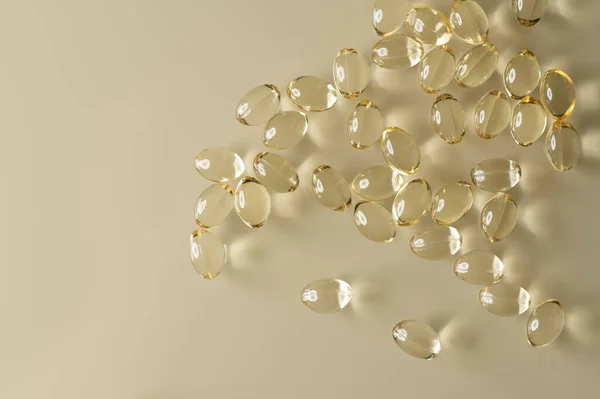 yellow gel transparent capsules of vitamin D poured in a bunch on a light background