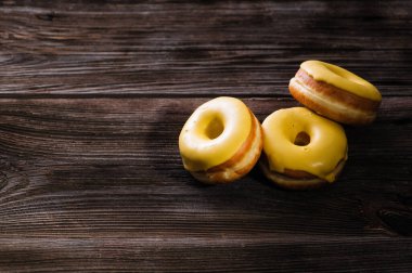 Tahta bir masada muzlu, üç tane parlak sarı çörek. Lezzetli kahvaltı, mesaj için yer.
