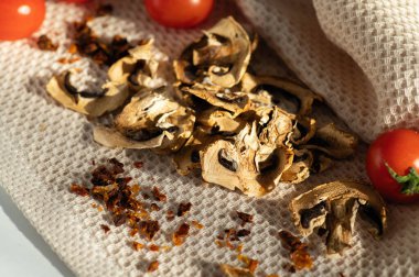 Çeri domatesli kurutulmuş mantar şampiyonları, gün ışığında masaya saçılmış, boş, yarı bitmiş ürünler, pişirmek için katkı maddesi.