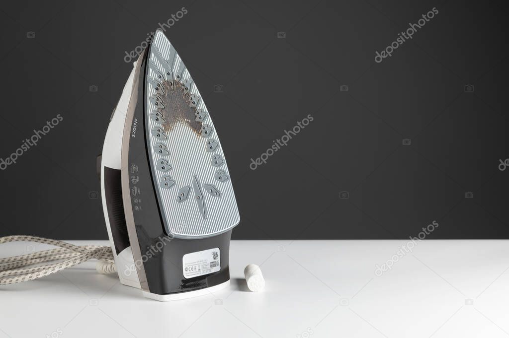 dirty steam iron, pencil cleaner, on white table, gray background, empty space, space for text